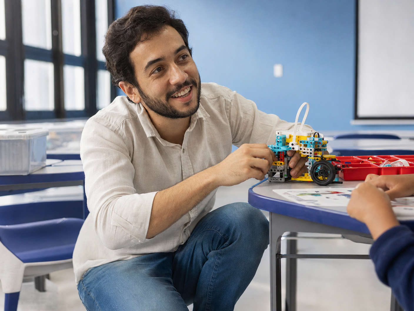 Marcos, professor de ciências, montando um robô de LEGO com um aluno em uma sala de aula